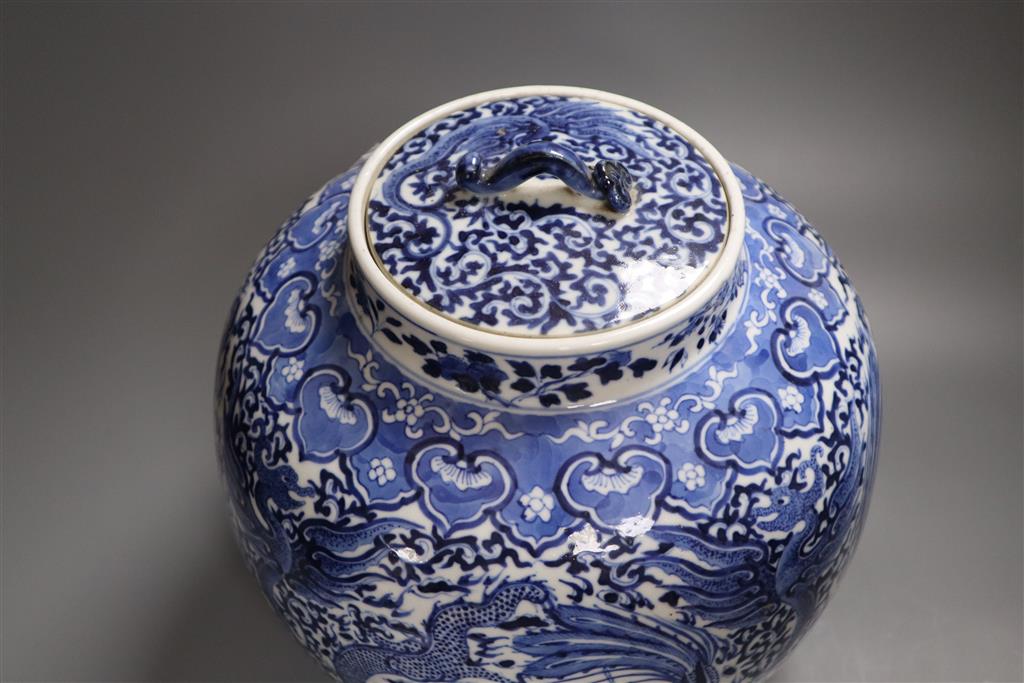 A 19th century blue and white water jar and cover, painted with dragons and birds, with inner cover and two later jars and covers